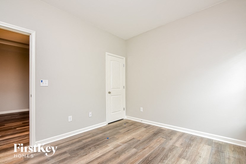 a bedroom with wood flooring and white walls and a door