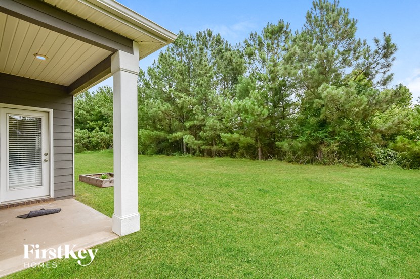 a backyard with a lawn and trees and a house with a porch