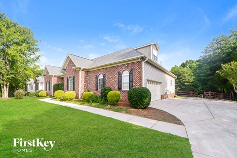 a large brick house with a driveway and lawn