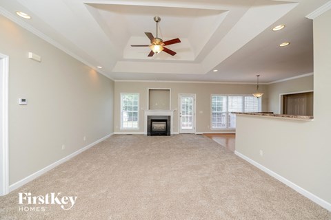 an empty living room with a fireplace and a ceiling fan