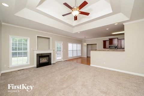 an empty living room with a fireplace and a ceiling fan