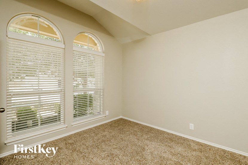 an empty bedroom with large windows and carpeting