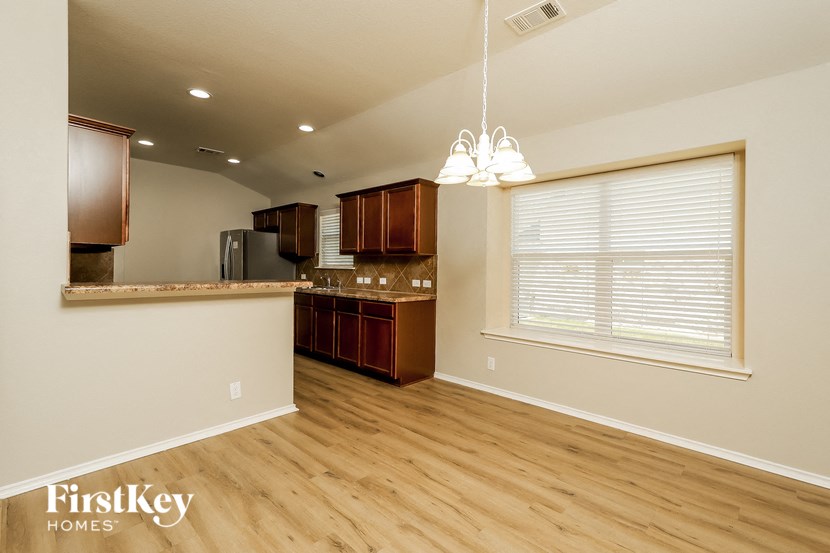 an empty kitchen with a large window and wooden floors
