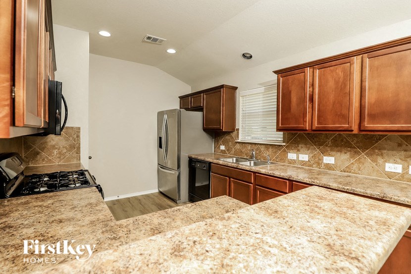 a kitchen with granite counter tops and a stainless steel refrigerator