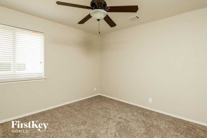 an empty room with a ceiling fan and a window