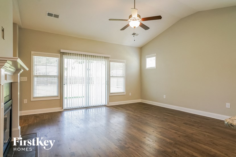 an empty living room with wood floors and a ceiling fan