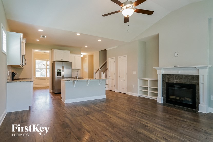 an empty living room with a fireplace and a kitchen