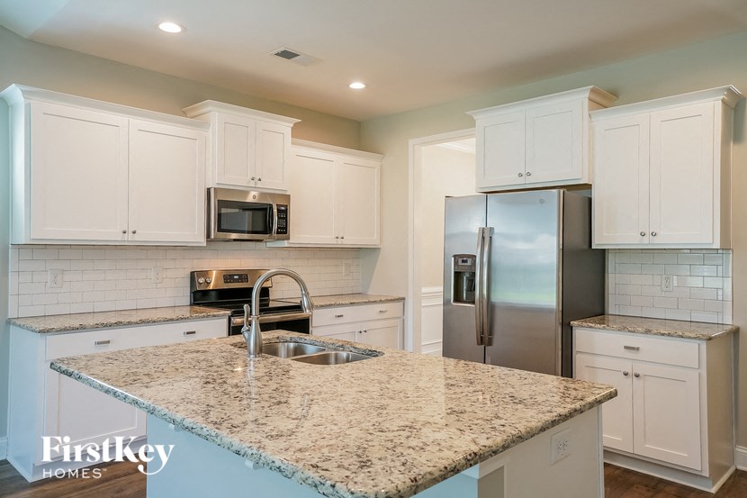a kitchen with white cabinets and a granite counter top