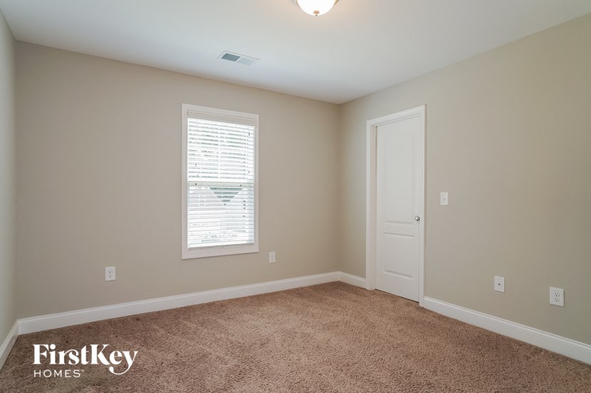 a bedroom with carpet and a door and a window