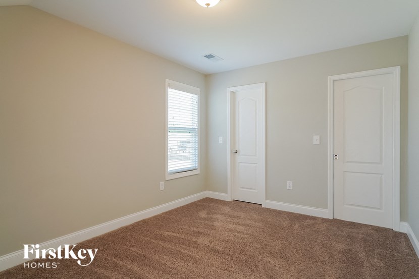 a bedroom with a carpeted floor and two doors and a window