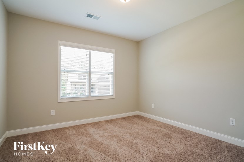 a bedroom with a window and a carpeted floor