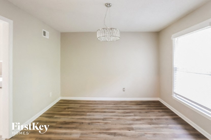 a empty living room with wood floors and a chandelier