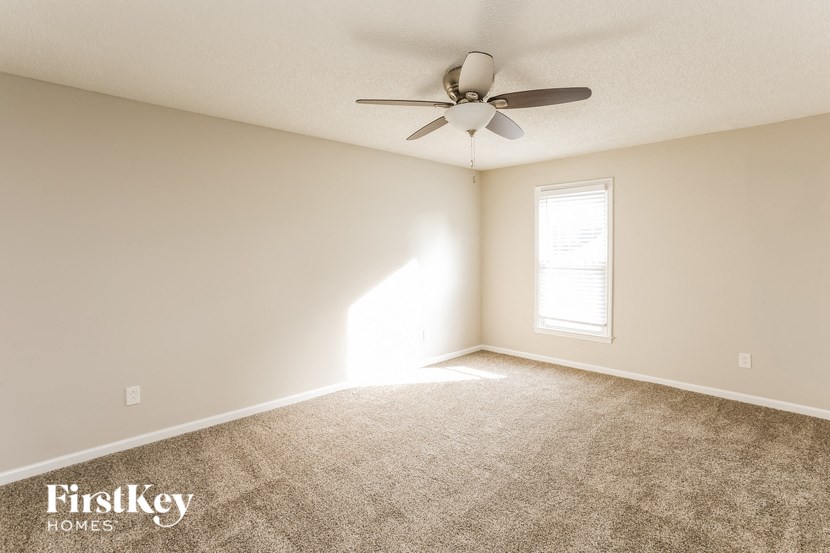a carpeted living room with a ceiling fan and a window