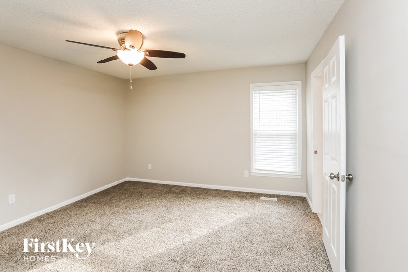 a bedroom with a ceiling fan and a carpeted floor