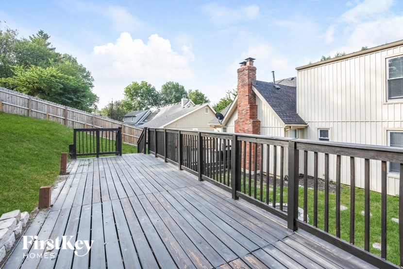 a backyard deck with a fence and a brick house