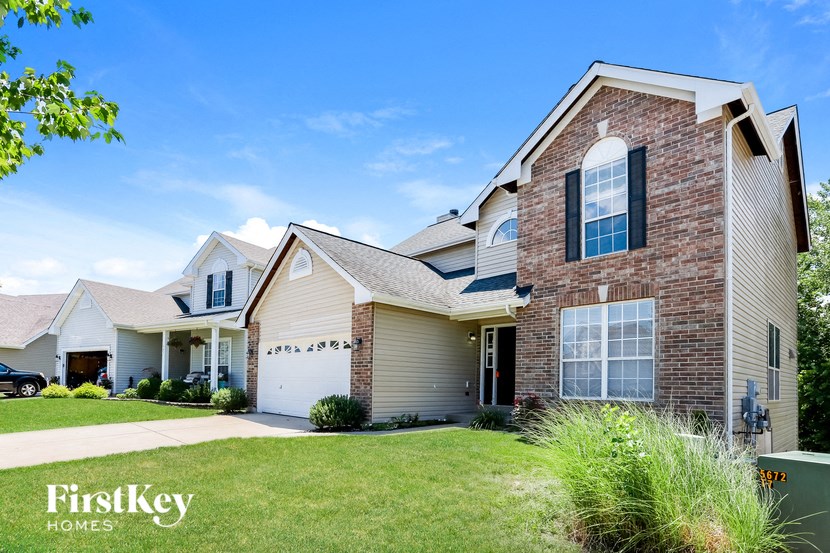 a brick house with a white garage door and a lawn
