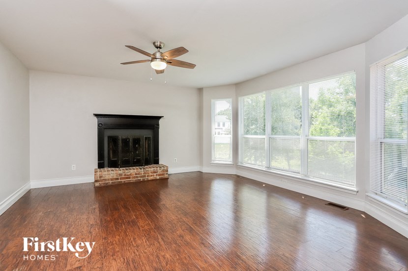 a living room with wood floors and a fireplace and a ceiling fan