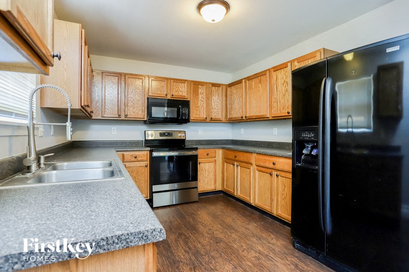 a kitchen with black appliances and wooden cabinets and granite counter tops