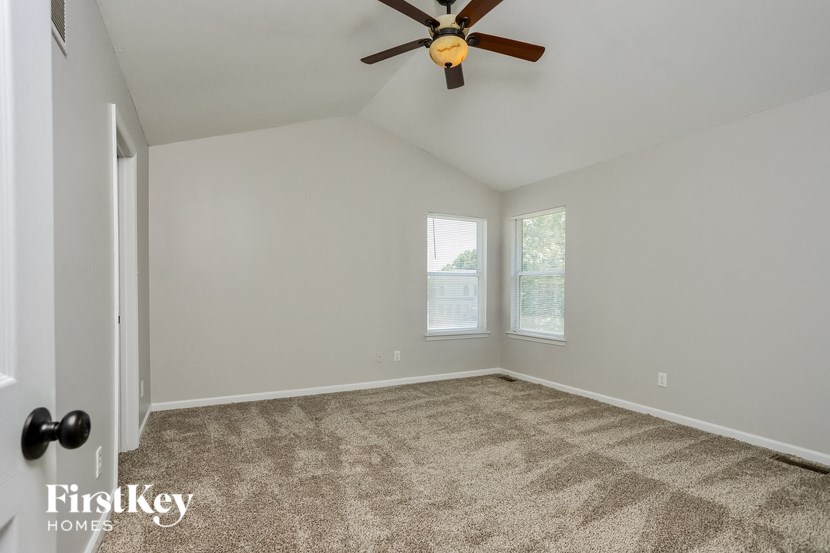 the living room of a home with carpet and a ceiling fan