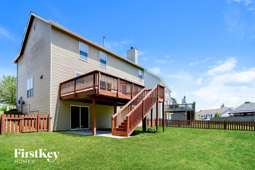 the back of the house with a deck and a wooden staircase