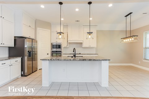 a kitchen with white cabinets and a marble counter top