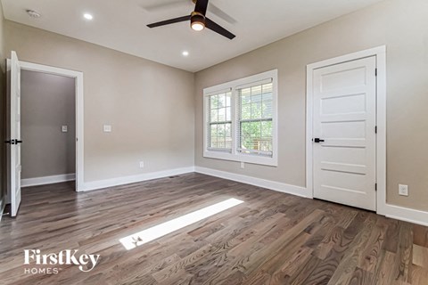 an empty living room with a white door and a ceiling fan