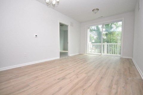 an empty living room with a large window and wooden floors