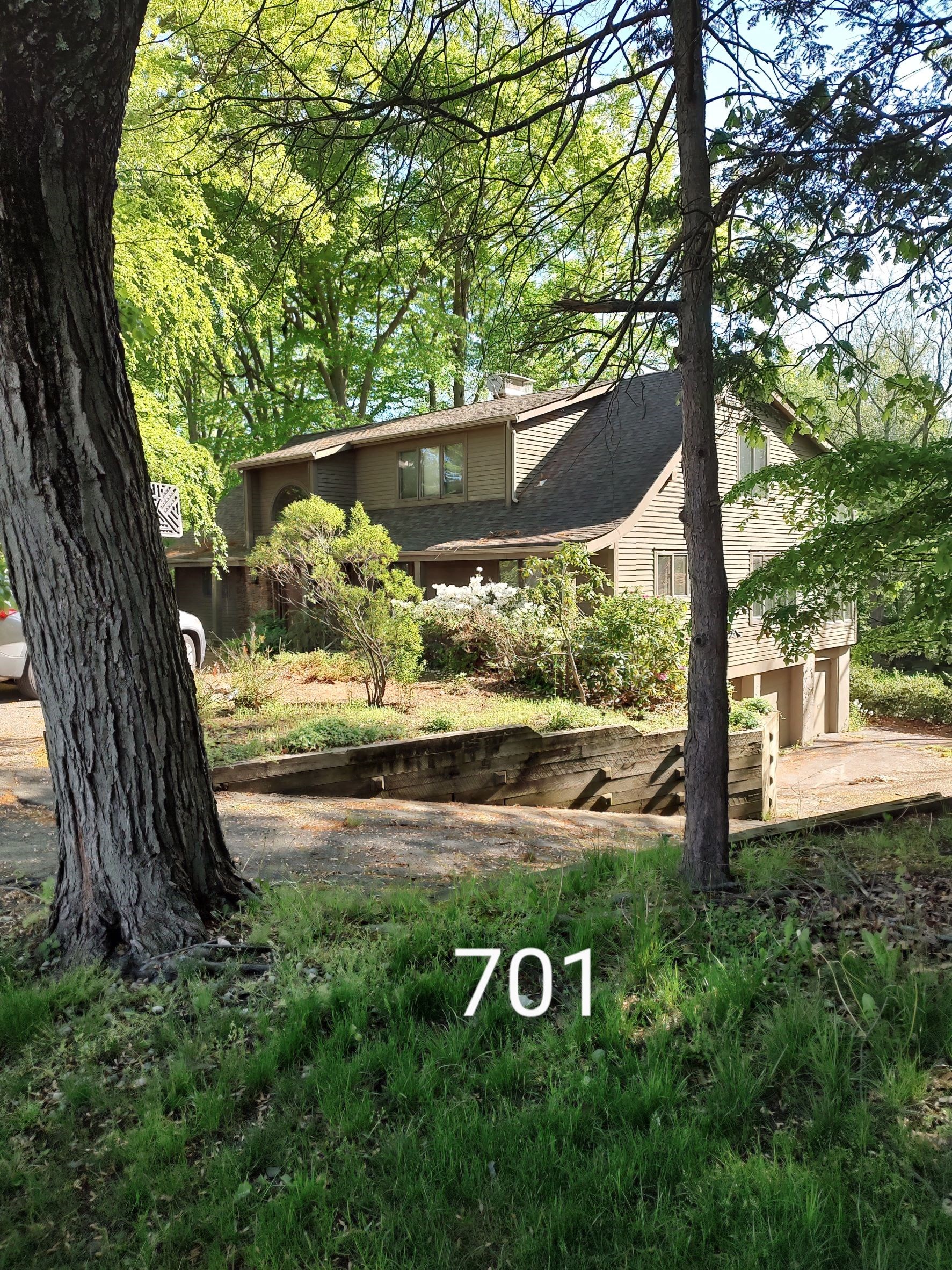 a view of the front of a house with a deck and a tree