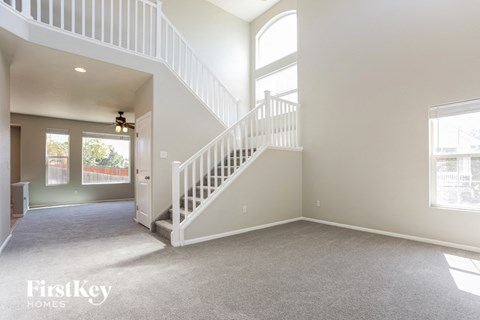 A spacious living room with a staircase leading to the upper floor.