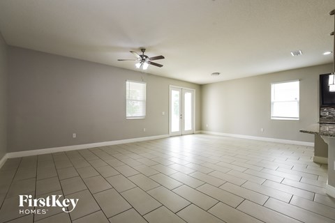 A spacious room with a fan and tile flooring.