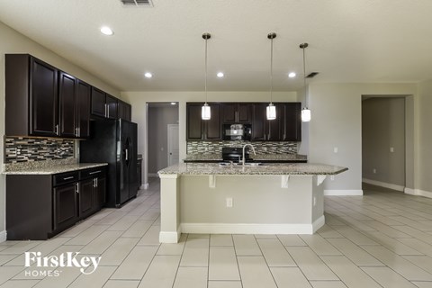 A kitchen with black cabinets and a granite countertop.