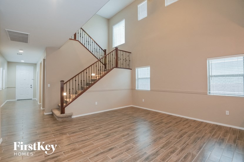 A spacious room with wooden flooring and a staircase with a railing.