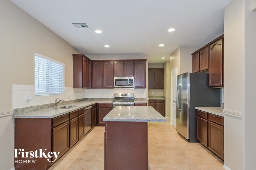 A kitchen with brown cabinets and a marble countertop.