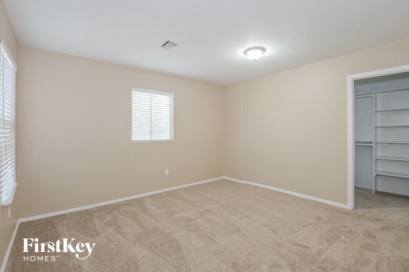 A room with a carpeted floor and a window with blinds.