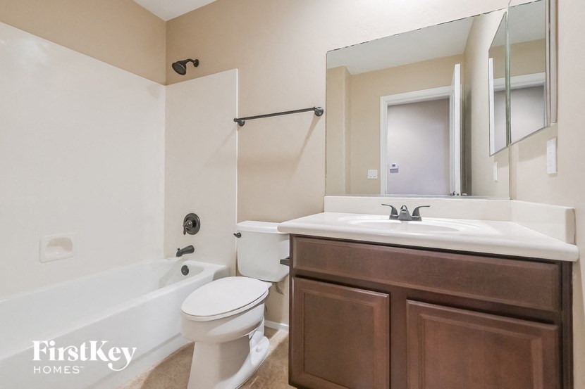 A bathroom with a white toilet, a white sink, and a brown cabinet.