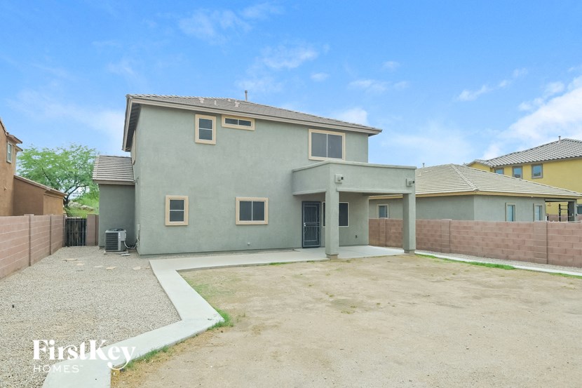 A grey house with a white fence and a gravel driveway.