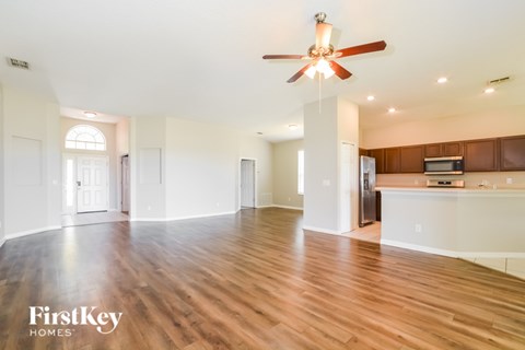A spacious living room with wooden floors and a ceiling fan.