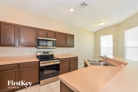 A kitchen with brown cabinets and a stove top oven.