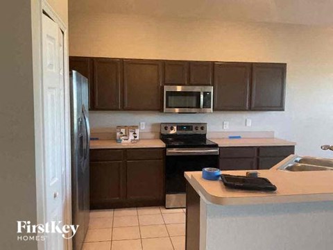 A kitchen with a refrigerator, microwave, oven, and sink.