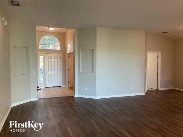 A room with wooden floors and a large window is available for rent.