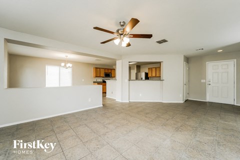 A spacious living room with a ceiling fan and tiled floor.