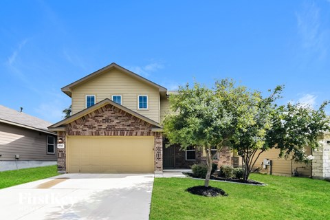 A house with a garage and a tree in front.