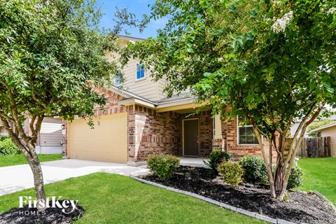 A house with a garage and a tree in front of it.