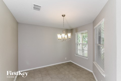 A well-lit room with a chandelier and a window with blinds.