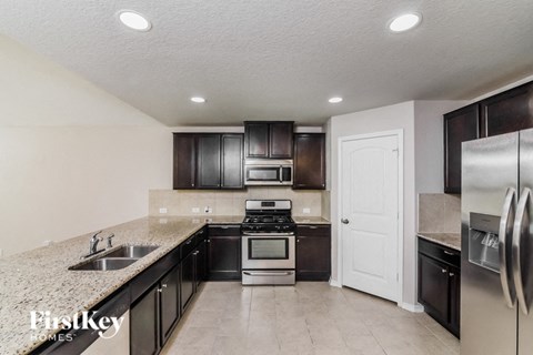 A kitchen with a sink, stove, and refrigerator.