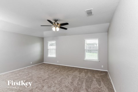 A room with a carpeted floor and a ceiling fan.