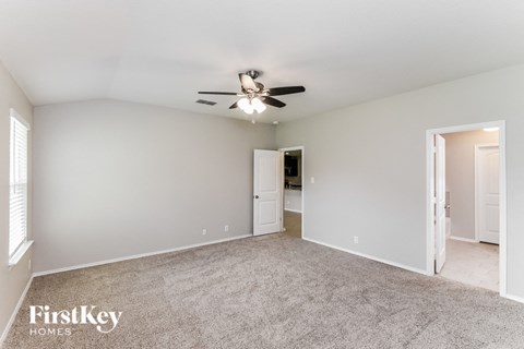 A spacious room with a ceiling fan and carpeted floor.