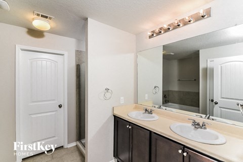 A bathroom with a white door, two sinks, and a mirror.