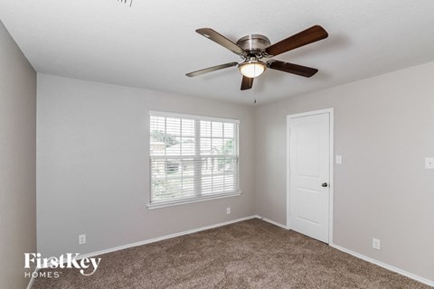 A room with a ceiling fan and a window with blinds.