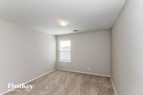 A room with a carpeted floor and a window with blinds.